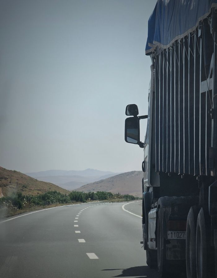 Mastering the First Impression: Your intriguing post title goes here Truck on a winding highway in Douar Ouled El Mesnaoui, Morocco, set in a rocky landscape.